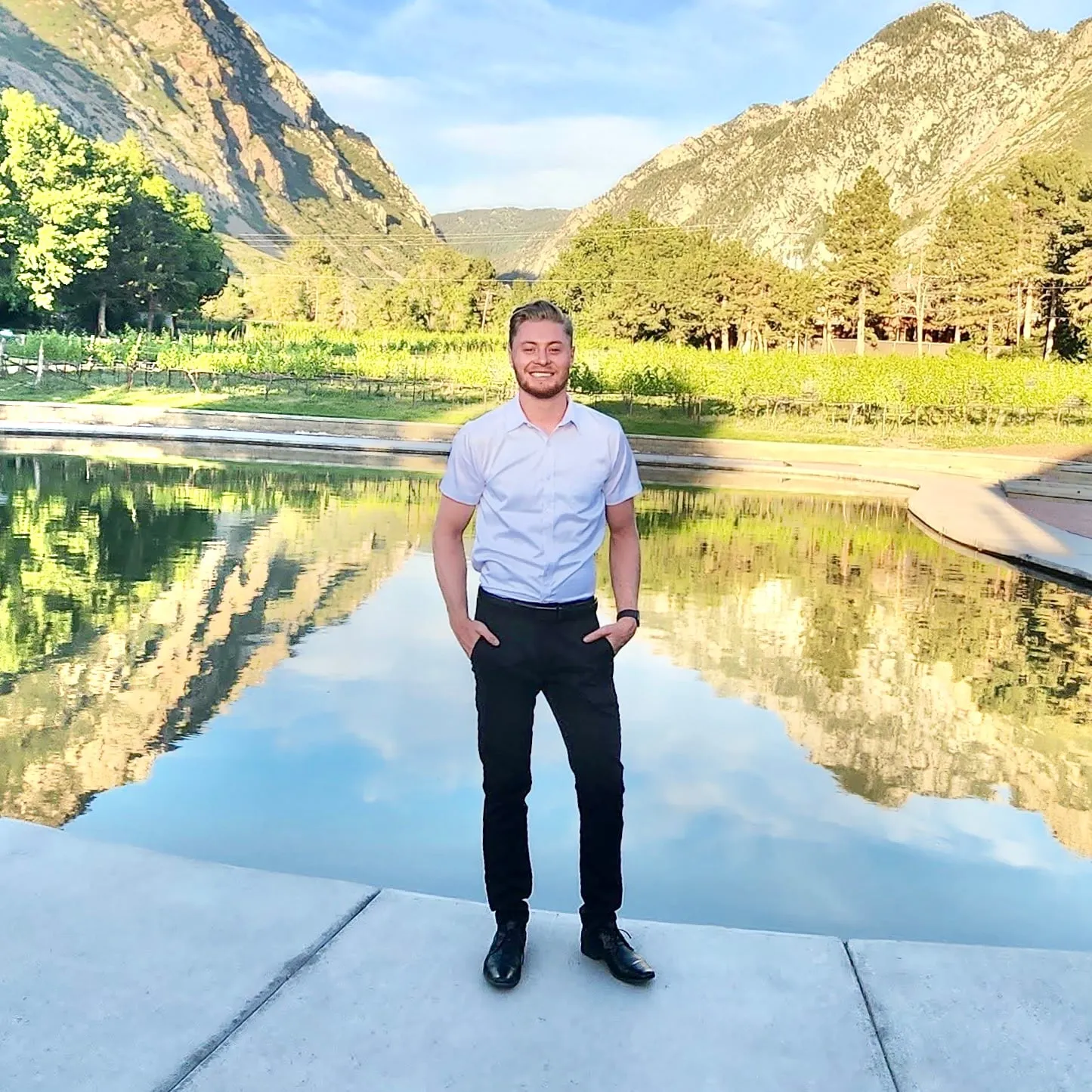 Jeremy K. Adamson standing by a reflecting pool, mountains behind.